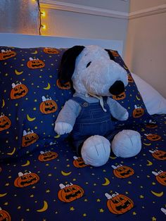 a stuffed dog sitting on top of a bed covered in pumpkins and jack - o'- lanterns