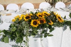 the table is set with sunflowers and greenery