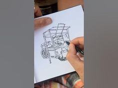 a person holding a piece of paper with a drawing of a truck on it in front of them