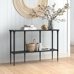 a black shelf with books and vases on it in front of a white wall