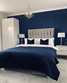 a bedroom with blue walls, white furniture and a chandelier hanging from the ceiling