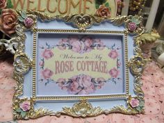 a welcome sign with roses on it in front of a pink and gold table cloth