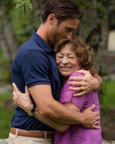 a man and woman hugging each other in the park