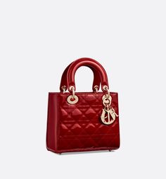 The Lady Dior bag epitomizes the House's vision of elegance and beauty. Sleek and refined, the timeless style is crafted in cherry red patent calfskin with Cannage stitching, creating the instantly recognizable quilted texture. Pale gold-finish metal signature D.I.O.R. charms embellish and illuminate its silhouette. Featuring a thin, removable leather shoulder strap, the small Lady Dior bag can be carried by hand or worn crossbody.. Dior Purse, Lady Dior Handbag, Dior And I, Womens Designer Bags, Small Lady, Christian Dior Couture, Luxury Purses, Dior Handbags, The Lady