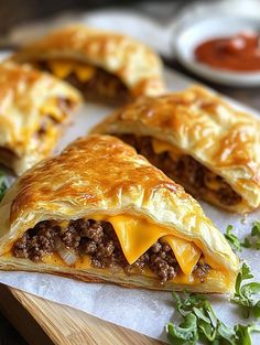 two meat and cheese pastries on a cutting board