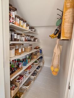 an organized pantry with lots of food in baskets and hanging utensils from the ceiling