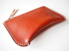 Simple yet unique formed zipped pouch.Using two types/colours of vegetan leather.Has a inside pocket.Able to use as a cosmetic bag, clutch bag, wallet, travel wallet and more.- Made from 100% Vegetable tanned leather- Hand stitched with waxed thread- Edges are burnished to smooth sheen- YKK metal zipper- Comes with 100% cotton bagApproximate Dimensions: W 8" x H 5" x D 1.50'' W 20cm x H 13cm x D 4cmZipper length: 7"18cmPersonalisation (optional)- Complimentary personalisation is available.- You Leather Pouches, Leather Zip Pouch, Small Leather Wallet, Leather Clutch Bag, Leather Card Case, Leather Coin Purse, Travel Wallet, Leather Hats, Leather Projects