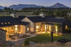 an aerial view of a house at night with mountains in the background and lights on