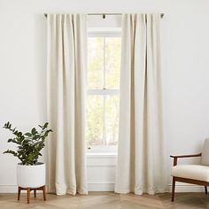 a living room with a chair, window and potted plant