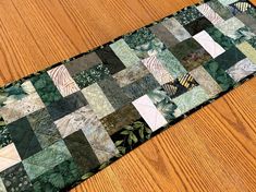 a green patchwork table runner on a wooden floor