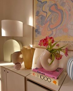 a vase with flowers sitting on top of a table next to a book and lamp