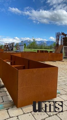 some very big metal boxes on the ground in front of some mountains and sky with clouds