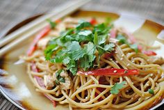 a plate full of noodles and vegetables with chopsticks