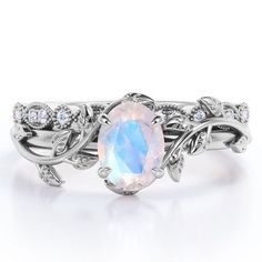 Paint your love story with this Art Deco Filigree Milgrain - 1.5 Carat Egg Cut Blue Moonstone and Moissanite - Beautiful Leaf Bridal Ring Set - 18K White Gold Plating over Silver. Skillfully hand-cut into a nice oval cut by our skilled jewelers, this astounding moonstone wedding band set combines 1.3 carat moonstone engagement ring and .2 carat moissanite engagement ring on solid white gold plating over silver. Distinctive and extraordinary, this silver moonstone ring set is well-suited for thos Moonstone Ring Engagement, Moon Stone Ring, Opal Wedding Ring, Opal Wedding Ring Set, Rainbow Moonstone Engagement Ring, Milgrain Wedding Ring, Opal Wedding Band, Natural Opal Ring, Opal Wedding Rings