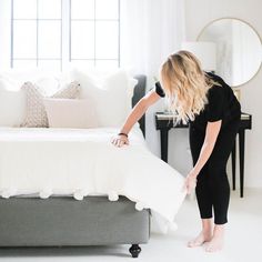 a woman standing over a bed in a room