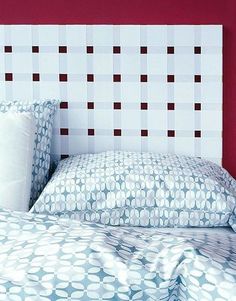 a bed with red walls and white headboard in a room that is well lit