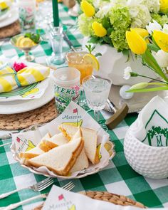 a table topped with plates and sandwiches on top of a green checkered table cloth