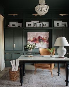 a desk with a lamp and pictures on the wall behind it in a living room