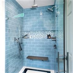 a bathroom with blue tiles on the walls and floor, along with a walk in shower