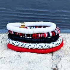 Our Red & Black Bracelet Set is the perfect way to bring a touch of luxury and style into your look. This exclusive set features five beautiful bracelets with playful pops of color. Whether you wear them together as a statement piece, or mix and match according to your mood, they're sure to make any ensemble more striking!Made from stretchy materials, each bracelet includes a single golden barrel bead that adds an elegant glimmer - for an eye-catching finish. Let them gracefully wrap around your Cheap Red Beaded Bracelets For Team Spirit, Red Adjustable Stacked Bracelets, Adjustable Stacked Red Bracelets, Trendy Red Beaded Bangle Bracelets, Trendy Red Stackable Beaded Bracelets, Trendy Red Stretch Bracelet For The Beach, Trendy Red Stretch Bracelet For Beach, Trendy Red Stackable Bracelets, Beautiful Bracelets