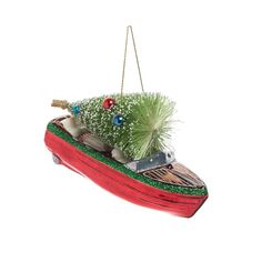 a christmas ornament with a boat and trees on it's side, hanging from a rope