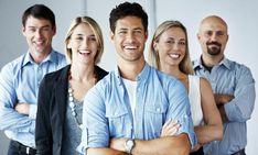 a group of people standing next to each other in front of a white wall with their arms crossed