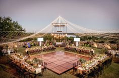 an outdoor tennis court with tables and chairs set up for a wedding reception at dusk