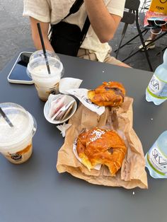 two pastries sitting on top of brown paper bags next to drinks and water bottles