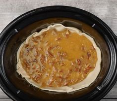 an uncooked pie in a crock pot with pecans around the edges