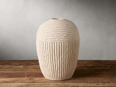 a white vase sitting on top of a wooden table