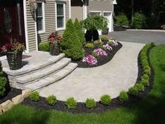 a driveway with landscaping and steps leading up to the house