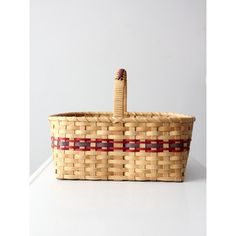 a woven basket with a red stripe on the bottom and a bottle in the middle