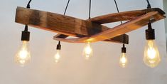 a wooden chandelier with five light bulbs hanging from it's center beam