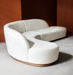 a white couch sitting on top of a floor next to a wooden frame chair and ottoman