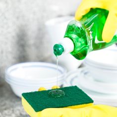 a person in yellow gloves is pouring green liquid into a bottle