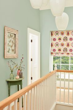 a room with blue walls, white railings and pink flowers on the window sill