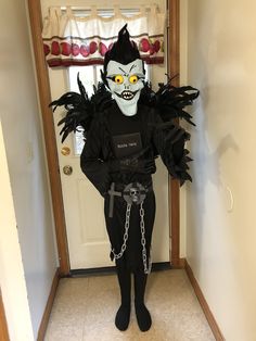 a person dressed up in a costume with chains and eyes on their face, standing in front of a door