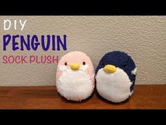 two small stuffed penguins sitting on top of a wooden table next to a wall with the words diy penguin sock plush