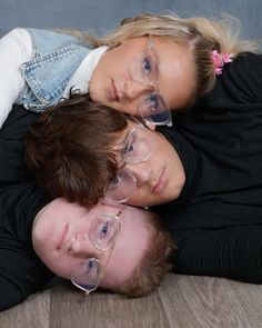 two people are laying on the floor with their arms around each other and wearing glasses