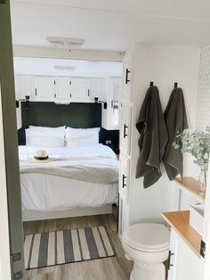 a white bed sitting next to a bathroom on top of a wooden floor