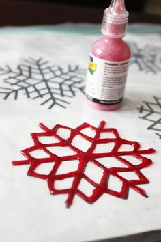 a bottle of paint sitting on top of a table next to a snowflake