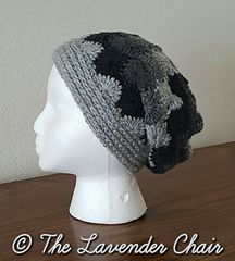 a white mannequin head wearing a gray and black knitted hat on top of a wooden table