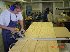 a man using a circular saw to cut plywood planks in a wood shop