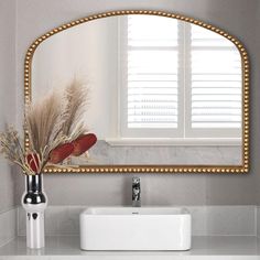 a bathroom sink with a mirror above it and a vase on the counter next to it