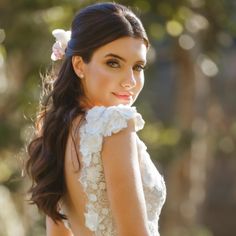 a beautiful woman in a white dress posing for the camera with her hands on her hips