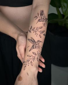 a woman's arm with a bird and flower tattoo on her left wrist,