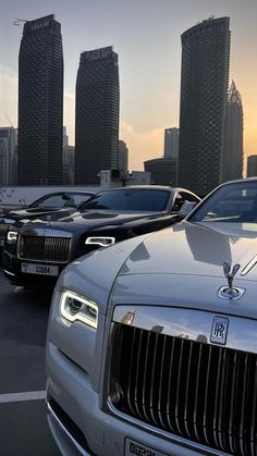 a row of rolls royces parked in front of tall buildings with skyscrapers in the background