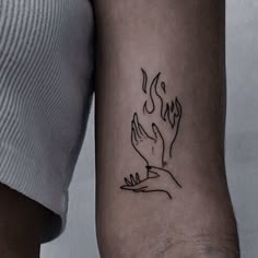 a woman's arm with a tattoo on it that has a hand holding a flame