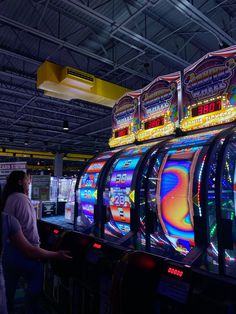 two women standing next to slot machines in a casino room with neon signs on them