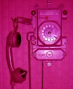 an old fashioned telephone is shown in pink neon light, with the phone on it's side